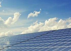 Sleek modern solar panels under a vibrant blue sky with clouds, symbolizing clean energy.